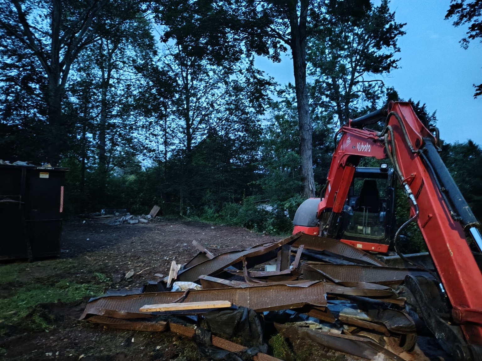 Excavator handling demolition debris during a Carey’s Enterprise site-clearing project