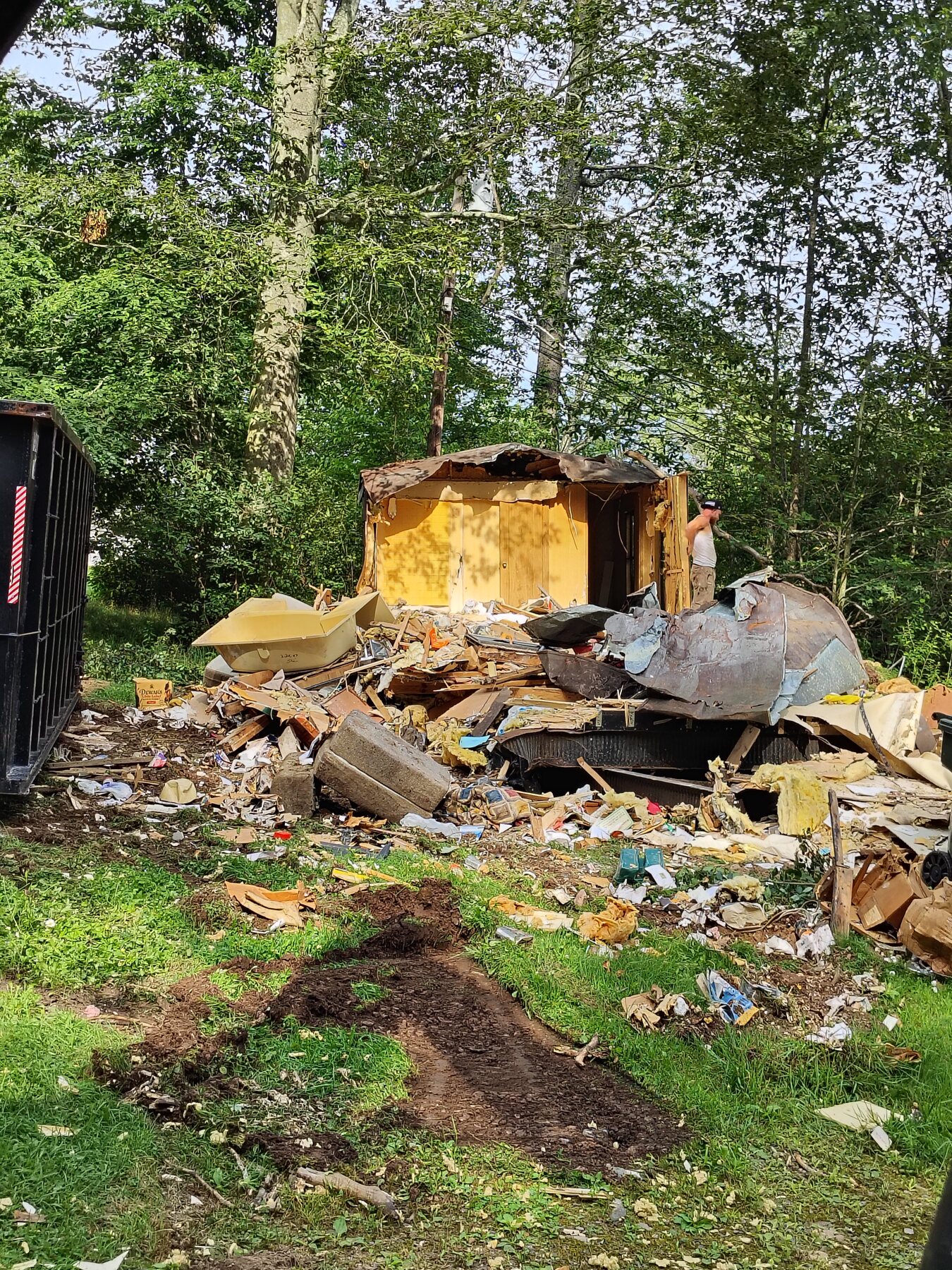 Mobile-home demolition and site clearing: Before — trailer being torn down